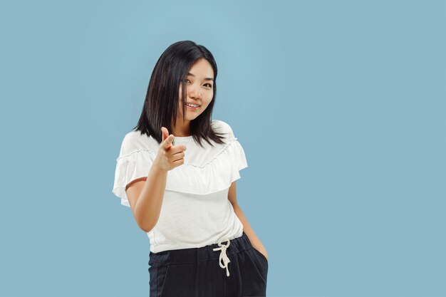 Retrato de medio cuerpo de la joven coreana sobre fondo azul.