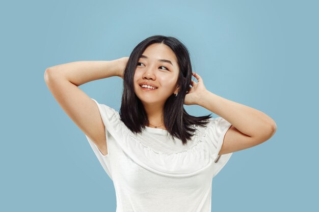 Retrato de medio cuerpo de la joven coreana sobre fondo azul.