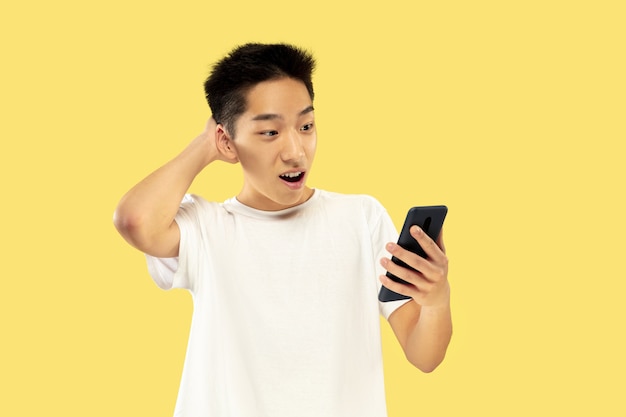 Retrato de medio cuerpo del joven coreano en la pared amarilla
