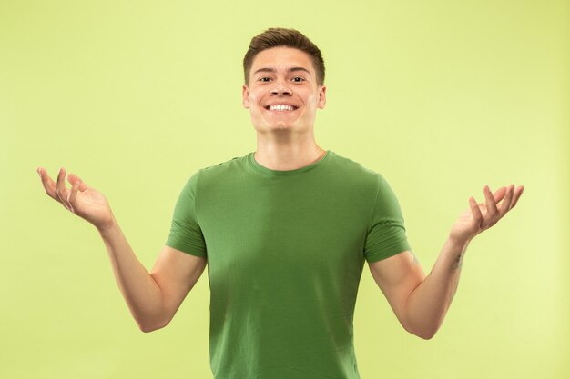 Retrato de medio cuerpo del joven en la pared verde del estudio