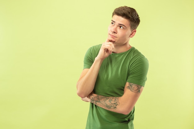 Foto gratuita retrato de medio cuerpo del joven en la pared verde del estudio