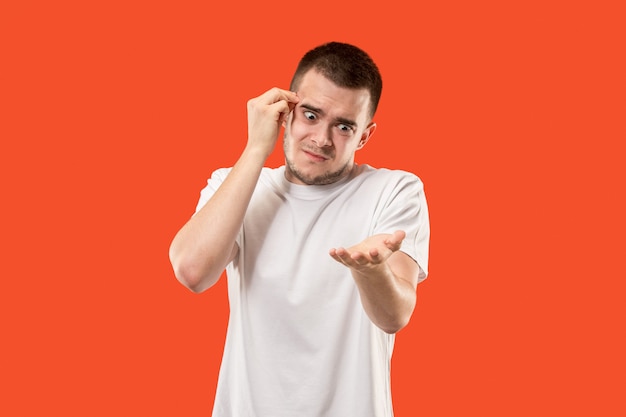 Retrato de medio cuerpo masculino hermoso aislado en el fondo anaranjado del estudio. El joven sorprendido emocional