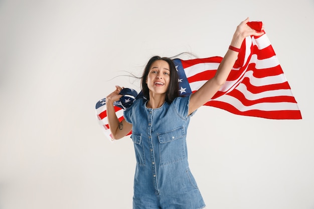 Foto gratuita retrato de medio cuerpo de una mujer joven con la bandera de los estados unidos aislado en el estudio blanco.