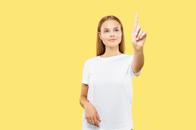 Retrato de medio cuerpo de la mujer joven caucásica en estudio amarillo