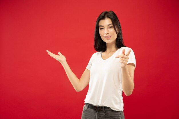 Retrato de medio cuerpo de la mujer joven caucásica en estudio rojo