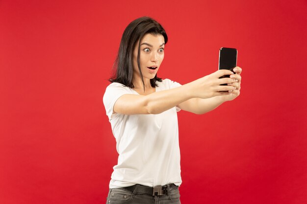 Retrato de medio cuerpo de la mujer joven caucásica en estudio rojo