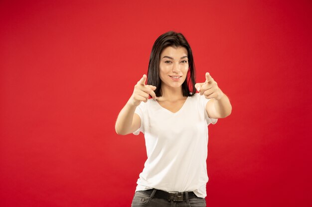 Retrato de medio cuerpo de la mujer joven caucásica en estudio rojo