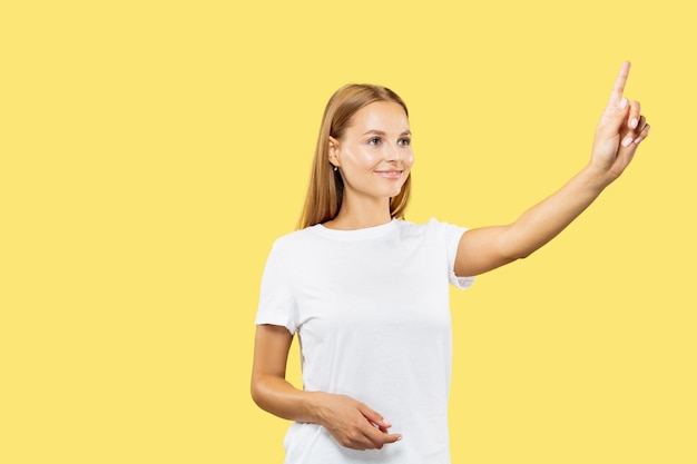 Retrato de medio cuerpo de la mujer joven caucásica sobre fondo amarillo de estudio. Hermosa modelo de mujer en camisa blanca