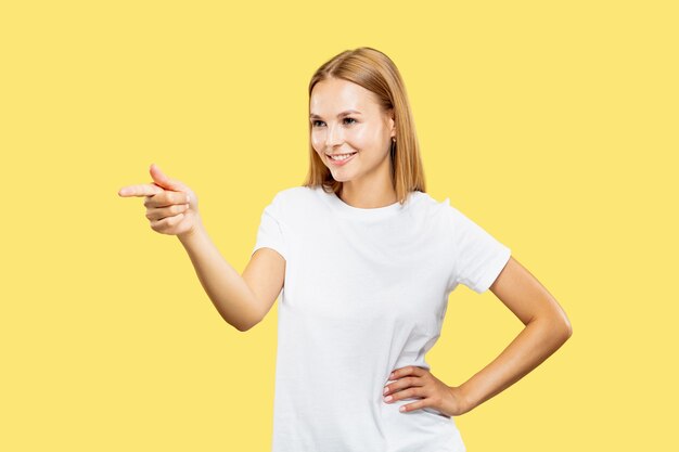 Retrato de medio cuerpo de la mujer joven caucásica sobre fondo amarillo de estudio. Hermosa modelo de mujer en camisa blanca