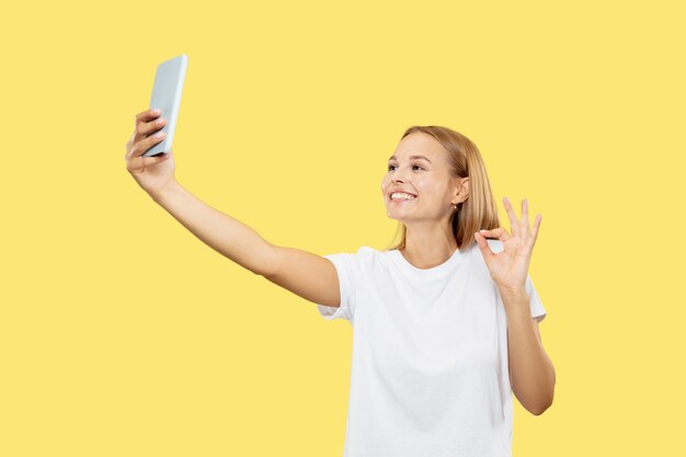 Retrato de medio cuerpo de la mujer joven caucásica sobre fondo amarillo de estudio. Hermosa modelo de mujer en camisa blanca