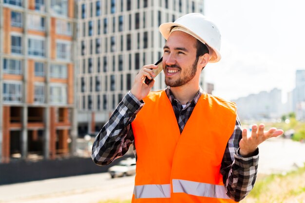 Retrato medio del ingeniero de construcción que habla en el teléfono