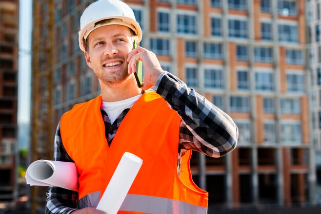 Retrato medio del ingeniero de construcción que habla en el teléfono