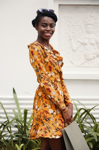 Retrato medio de niña afroamericana posando al aire libre con una bolsa de compras