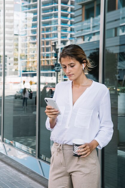 Retrato de un mensaje de texto de joven empresaria en teléfono inteligente