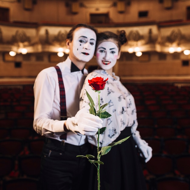 Retrato de mime pareja sosteniendo rosa roja