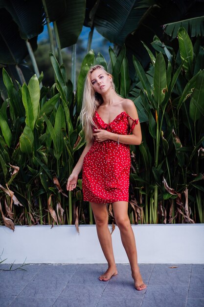 Retrato de moda al aire libre belleza natural joven mujer bonita con maquillaje ligero, aretes de estrella, pulsera y anillo. Mujer en vestido rojo de flores de verano