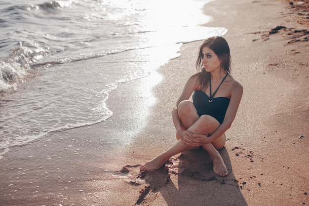 Retrato de moda al aire libre de dama bronceada en traje de baño sexual posando en la playa