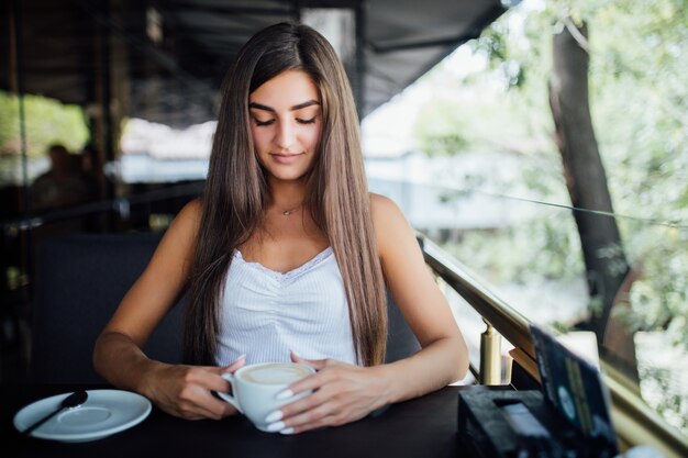 Retrato de moda al aire libre de la hermosa joven bebiendo té café