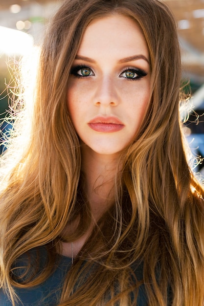 Retrato de moda al aire libre de mujer elegante con vestido maxi brillante, cabello largo hermoso, maquillaje brillante. Sol de la tarde.