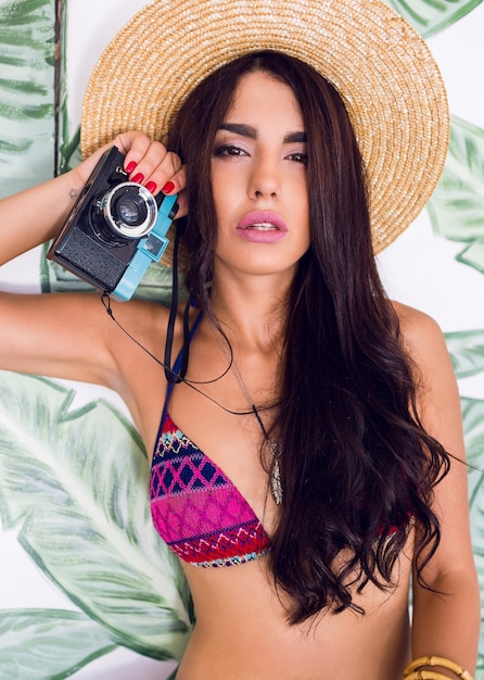 Retrato de moda al aire libre de mujer joven con estilo hipster en gorra de botín de moda con cámara retro.