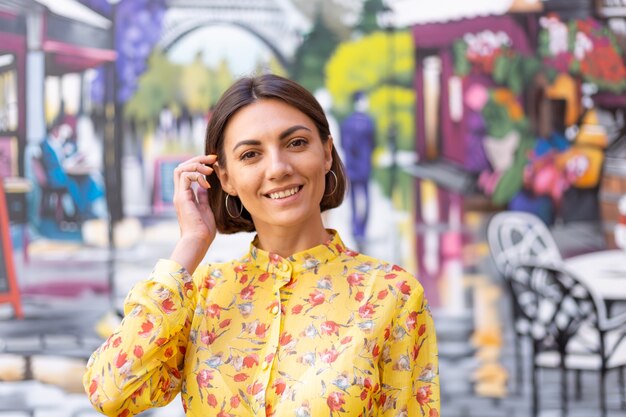 Retrato de moda al aire libre de mujer en vestido amarillo de verano en la pared colorida de la calle