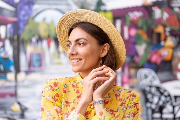 Retrato de moda al aire libre de mujer en vestido amarillo de verano en la pared colorida de la calle