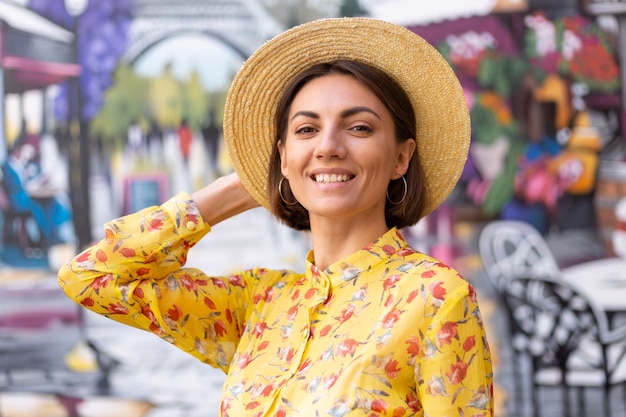 Retrato de moda al aire libre de mujer en vestido amarillo de verano en la pared colorida de la calle