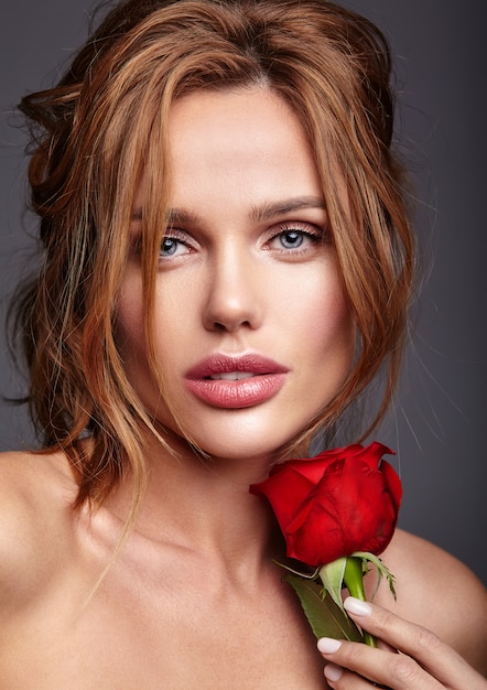 Retrato de moda de belleza de joven rubia modelo con maquillaje natural y piel perfecta con hermosa rosa posando