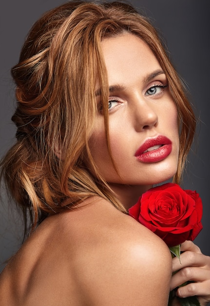 Retrato de moda de belleza de joven rubia modelo con maquillaje natural y piel perfecta con hermosa rosa posando