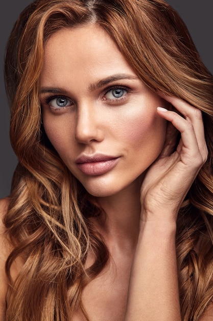 Retrato de moda de belleza de modelo joven rubia con maquillaje natural y piel perfecta posando. Tocando su cabello