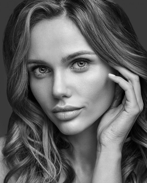 Retrato de moda de belleza de modelo joven rubia con maquillaje natural y piel perfecta posando. Tocando su cabello