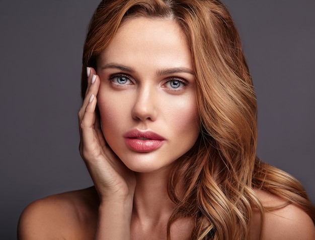 Retrato de moda de belleza de modelo joven rubia con maquillaje natural y piel perfecta posando. Tocando su cara