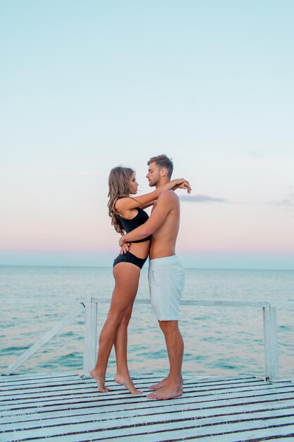 Retrato de moda de cerca al aire libre de una pareja muy sexy enamorada de abrazos en una increíble playa tropical con elegantes trajes de baño