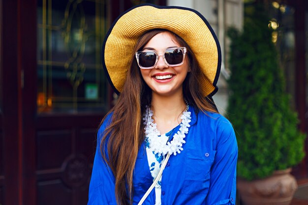 Retrato de moda de estilo de vida de ciudad de niña bonita feliz caminando sola divirtiéndose en la calle, luz del sol de la tarde, sombrero vintage vestido retro, estado de ánimo positivo feliz.