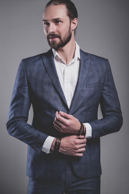 Foto gratuita retrato de moda guapo elegante hipster empresario modelo vestido con elegante traje azul posando en gris