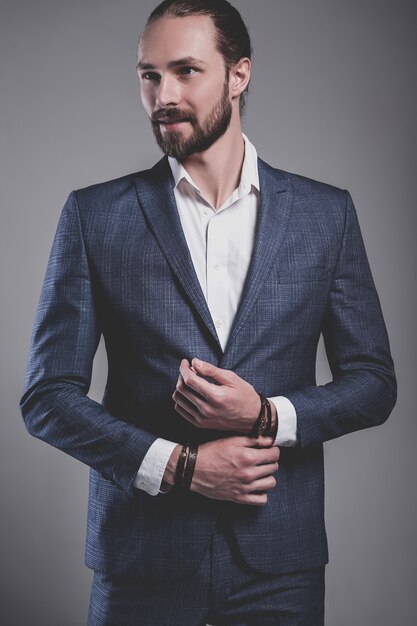 Retrato de moda guapo elegante hipster empresario modelo vestido con elegante traje azul posando en gris