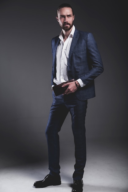 Retrato de moda guapo elegante hipster empresario modelo vestido con elegante traje azul posando en gris