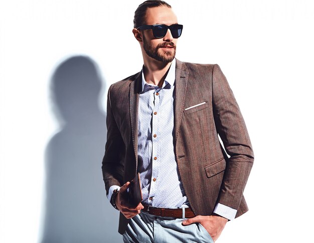 Retrato de moda guapo elegante hipster empresario modelo vestido con elegante traje marrón con gafas de sol