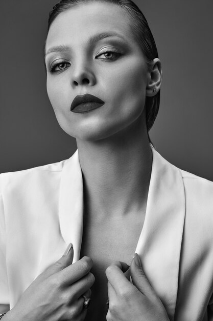 Retrato de moda hermosa mujer morena elegante modelo con maquillaje de noche y labios rojos en chaqueta blanca