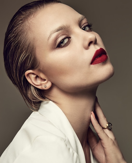 Retrato de moda hermosa mujer morena elegante modelo con maquillaje de noche y labios rojos en chaqueta blanca