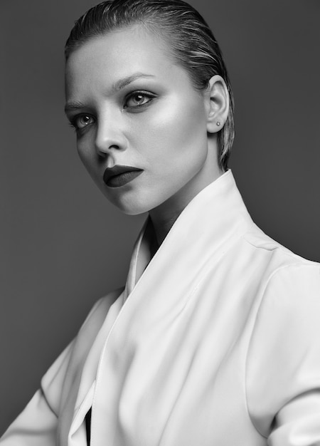 Retrato de moda hermosa mujer morena elegante modelo con maquillaje de noche y labios rojos en chaqueta blanca