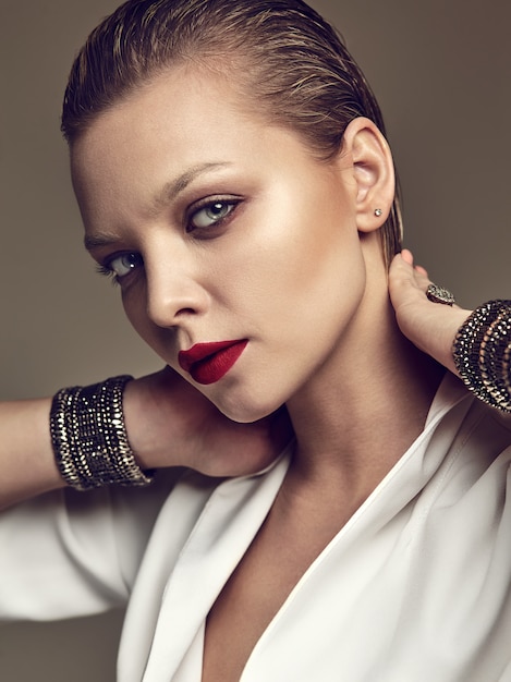 Retrato de moda hermosa mujer morena elegante modelo con maquillaje de noche y labios rojos en chaqueta blanca
