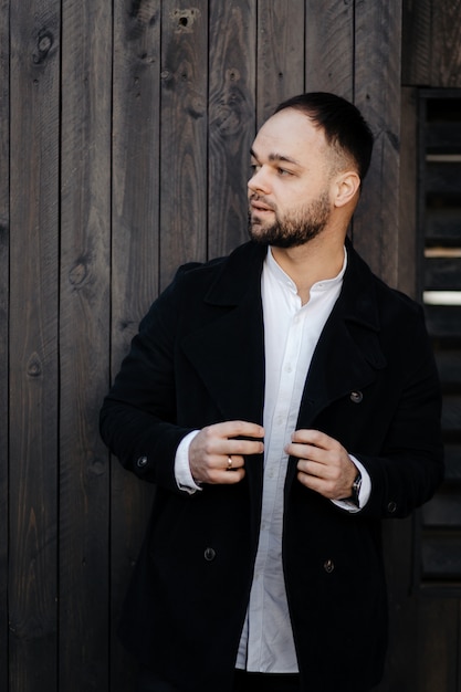 Retrato de moda hombre bien vestido con barba posando al aire libre