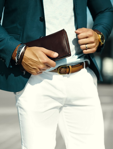 Retrato de moda de joven empresario guapo modelo hombre en traje de tela casual con accesorios en las manos