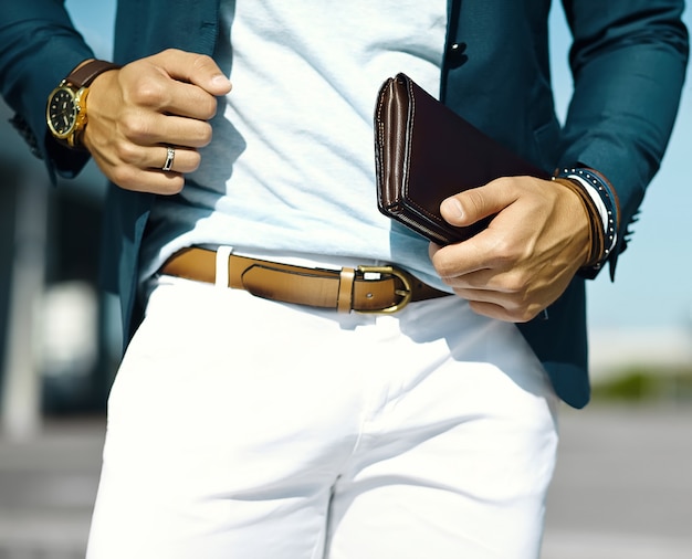 Retrato de moda de joven empresario guapo modelo hombre en traje de tela casual con accesorios en las manos