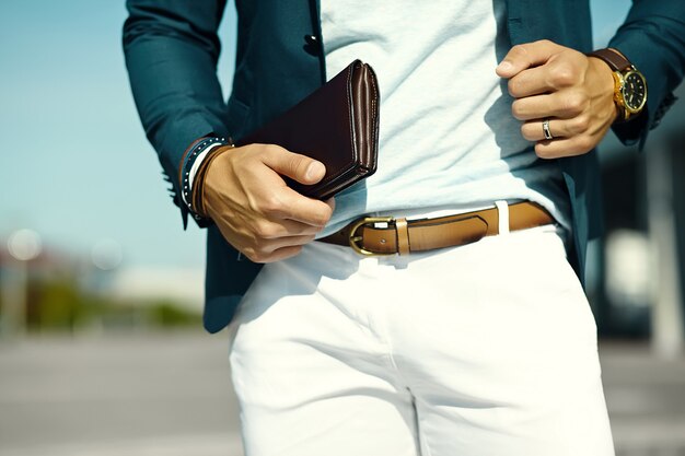 Retrato de moda de joven empresario guapo modelo hombre en traje de tela casual con accesorios en las manos