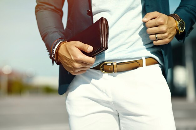 Retrato de moda de joven empresario guapo modelo hombre en traje de tela casual con accesorios en las manos