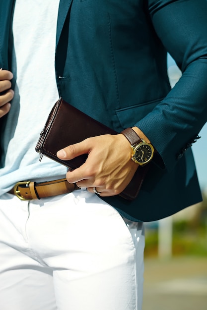 Retrato de moda de joven empresario guapo modelo hombre en traje de tela casual con accesorios en las manos