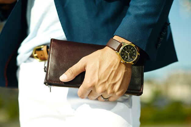 Retrato de moda de joven empresario guapo modelo hombre en traje de tela casual con accesorios en las manos