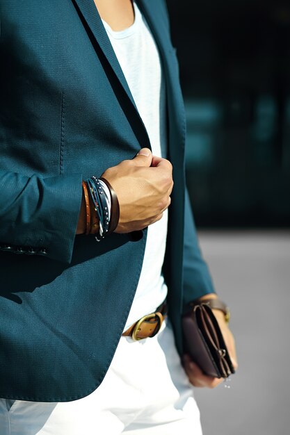 Retrato de moda de joven empresario guapo modelo hombre en traje de tela casual con accesorios en las manos